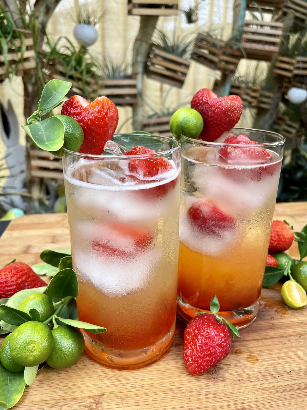 Two layered calamansi and strawberry spritzers with fresh strawberries and calamansi