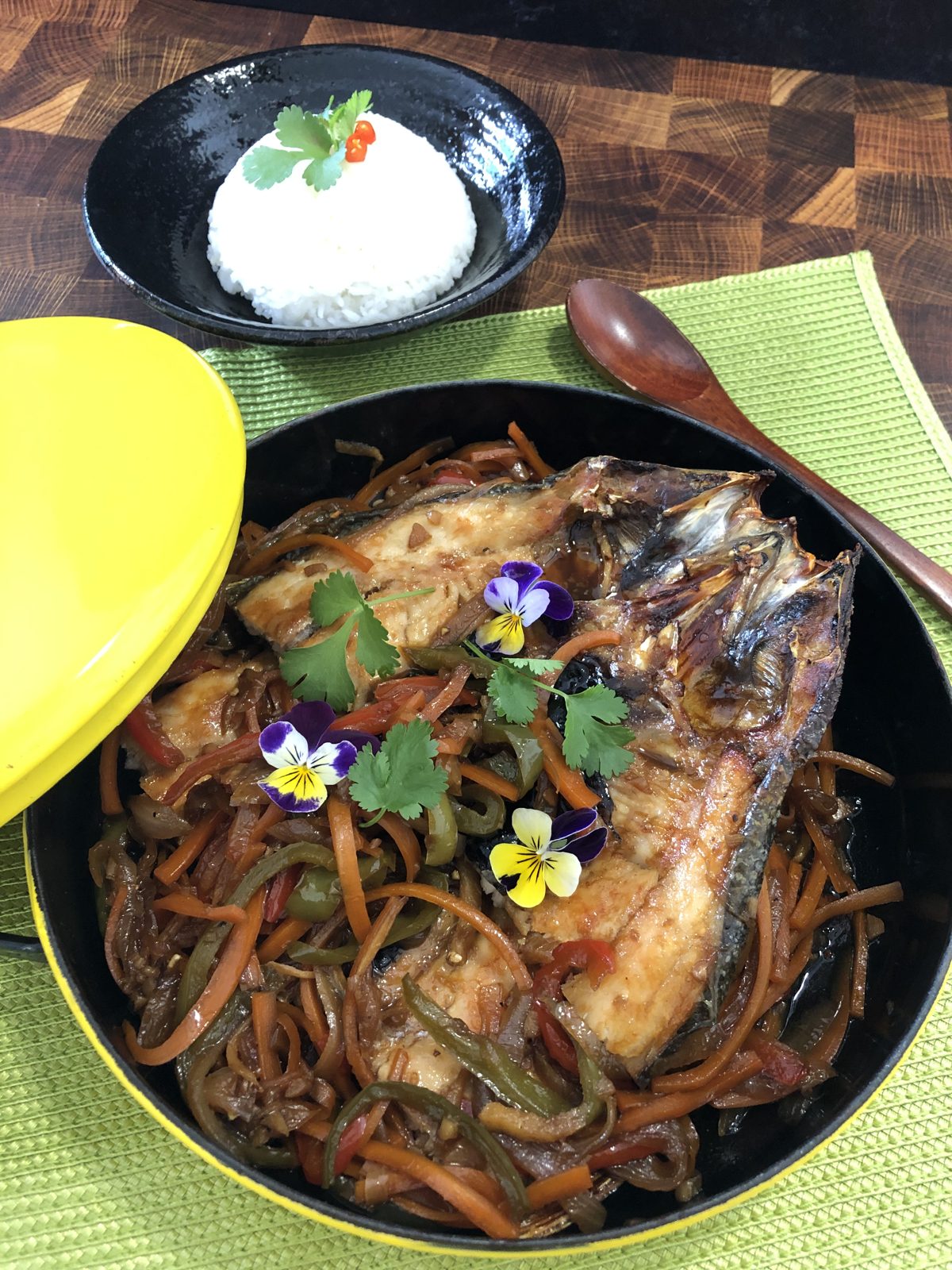 Fried fish escabeche topped with sweet and sour vegetables and edible flowers