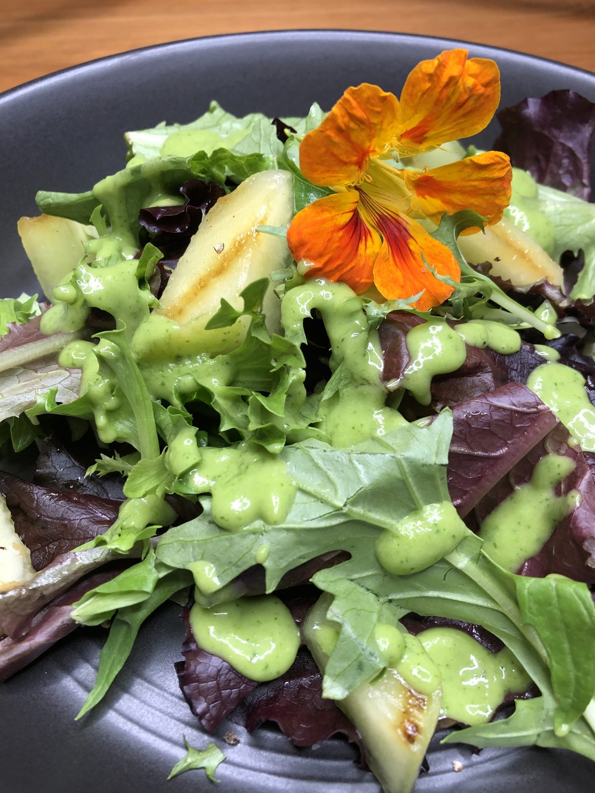 Honeydew melon salad on mixed greens with avocado dressing and a nasturtium flower