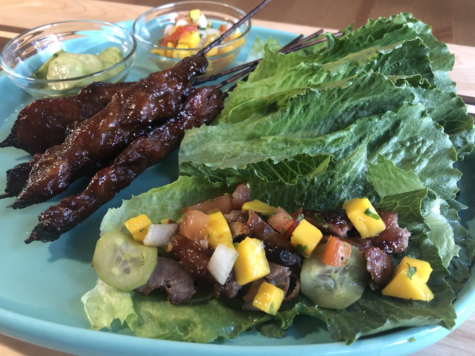 Pork BBQ skewers with lettuce wraps, mango salsa and cucumber pickles