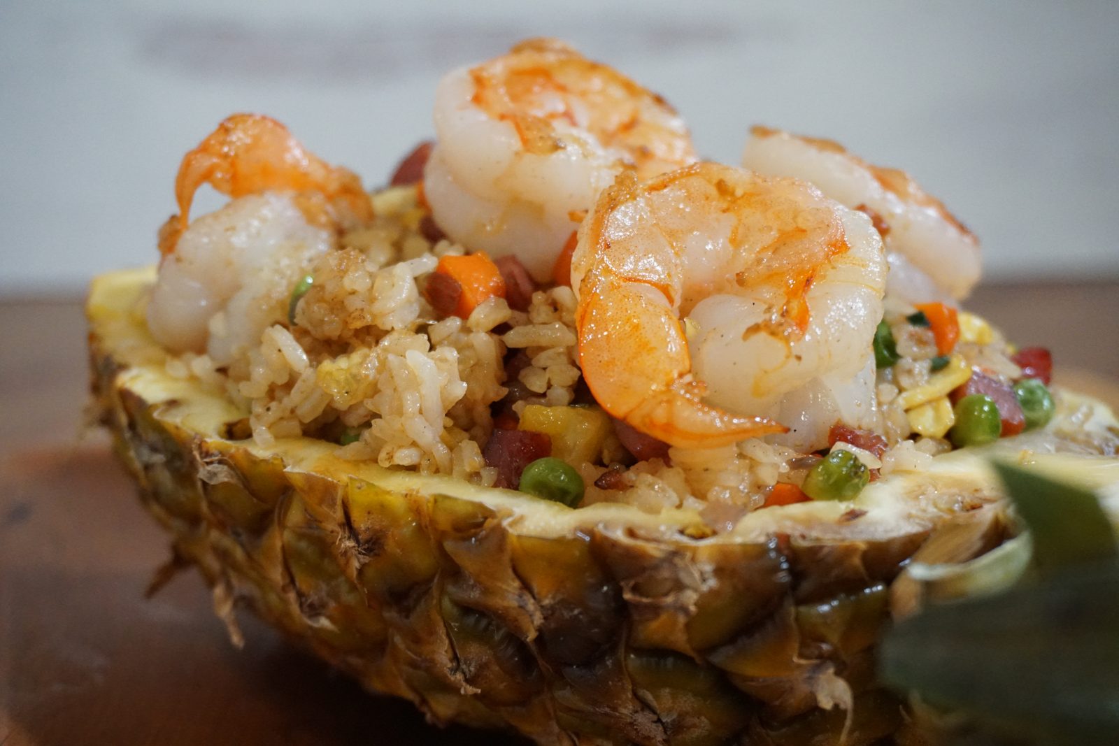 Tocino fried rice topped with shrimp, served in a pineapple half