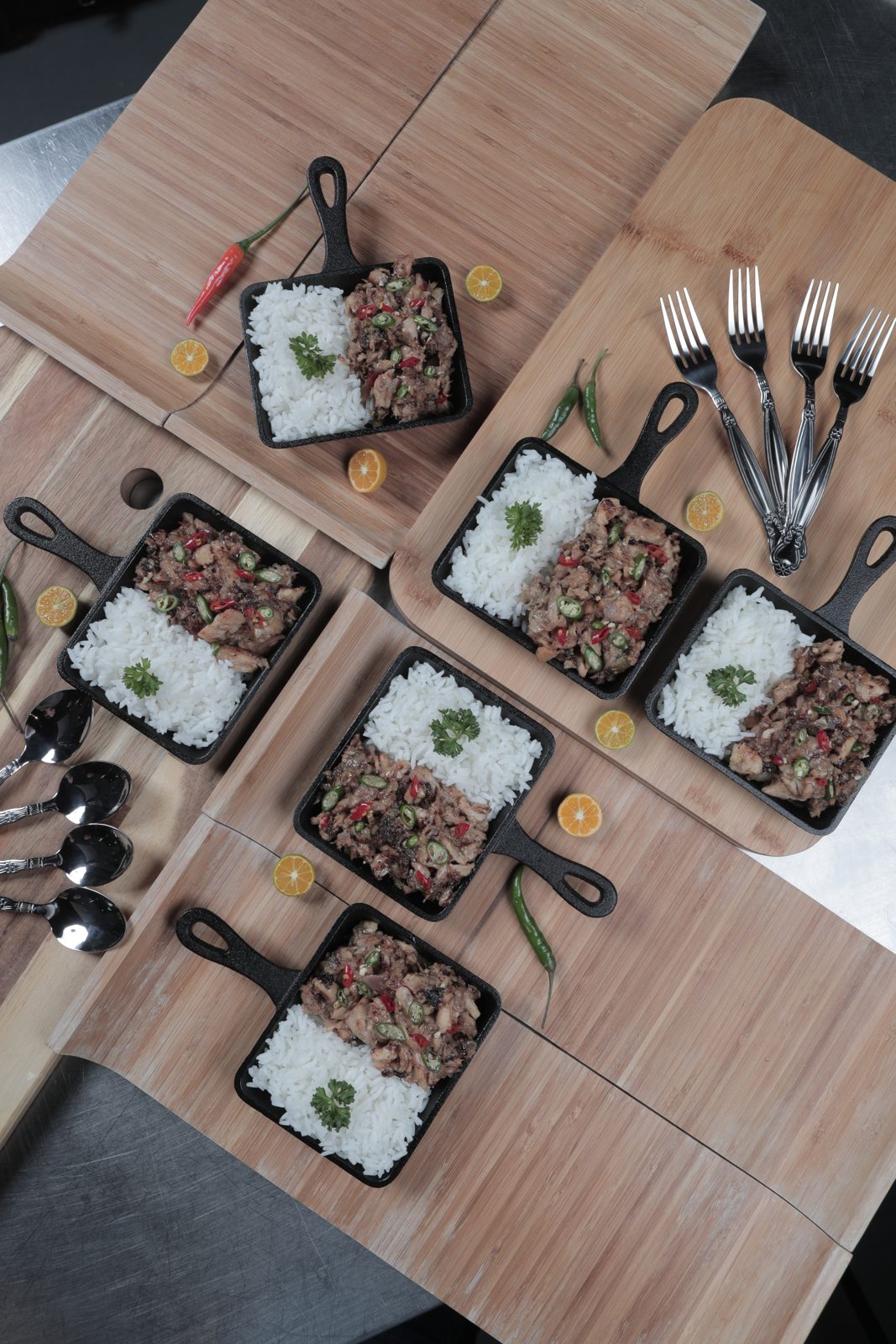 Sizzling sisig with rice in small cast-iron skillets, seen from above